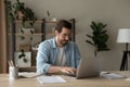 Focused young businessman freelancer engaged in distant work on laptop