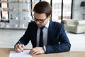 Focused young businessman putting signature on documents.