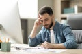 Focused young businessman sitting at desk in office and writing in notepad Royalty Free Stock Photo