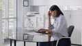 Focused young businesswoman sitting at desk and using laptop in modern office. Royalty Free Stock Photo