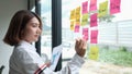 Focused young businesswoman writing new ideas on sticky notes on glass wall Royalty Free Stock Photo