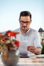 Focused businessman looking over sales reports and documents during coffee break