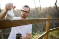 Young man in casual clothing painting wooden fence in his backyard