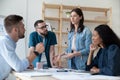 Focused young diverse employees listening to motivated skilled female professional. Royalty Free Stock Photo