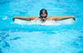 Bettering her time stroke by stroke. A focused young female swimmer doing the butterfly stroke.