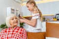 Focused young girl combing her grandmothers hair