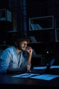 Focused young indian business man working online at night using laptop. Royalty Free Stock Photo