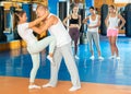 Young latina mastering knee kick while sparring with male opponent Royalty Free Stock Photo