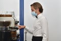 young male bartender wearing a surgical mask operating a bar espresso machine. Bartending and safety concept