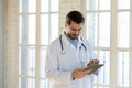 Focused young male doctor using electronic digital touchscreen gadget.