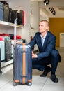 Focused young man carefully examines a travel suitcase