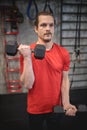 Focused young man doing biceps exercises with dumbbell weights