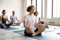 Focused young man sitting on yoga mat in lotus pose.