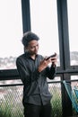 Focused young man using smartphone near window with cityscape view Royalty Free Stock Photo