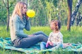 Focused young mother blows a balloon for her little cheerful daughter