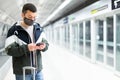 Traveler in mask standing with suitcase and phone on subway station platform Royalty Free Stock Photo