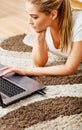 Focused young woman using laptop while lying on floor Royalty Free Stock Photo