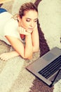 Focused young woman using laptop while lying on floor Royalty Free Stock Photo