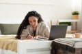 Focused young woman using laptop, working or studying online, taking notes during business meeting or webinar at home Royalty Free Stock Photo