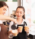 Focusing on beautiful Asian barista women cheering caucasian barista woman preparing takeaway hot coffee cup in cafe coffee shop