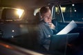 Focusing on work- businessman working on his laptop and paper on the back seat of the car Royalty Free Stock Photo