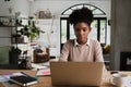 Focussed female student busy with online test for university, sitting in modern kitchen with coffee. Royalty Free Stock Photo