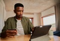 Focussed young adult black male using electronic tablet to make online purchase.