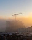 Fog blanket moving in at sunset over a construction site and crane Royalty Free Stock Photo