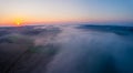 Fog-covered colorful farm fields with silhouettes of trees with bright orange sunrise in Roztocze Poland. Horiozntal Royalty Free Stock Photo