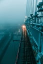 the fog covers the bridge as a train passes underneath it