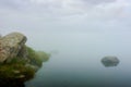 fog on the lake. grassy shore with rocks.