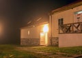 Fog landscape, bright and illuminated building, illuminated trees in the dark, the land is covered with colorful autumn leaves, Royalty Free Stock Photo