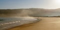 Fog and mist rising from a golden sand beach with gentle lapping waves