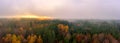 Fog over a autumn colored forest at the autumn season, a panoramic mystical view at the sunset shot by a drone. Royalty Free Stock Photo