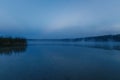 Fog over the lake, twilight over the lake, very dense fog, dawn, blue sky over the lake, the morning comes, the forest reflects in Royalty Free Stock Photo