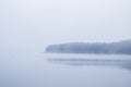Fog over the water at a lake with trees in the background Royalty Free Stock Photo