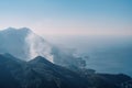 Fog rises high in the mountains over the blue sea at dawn Royalty Free Stock Photo