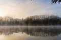 Fog rises on the water at sunrise on Lake Lanier in Georgia with a reflection of trees in the water in winter Royalty Free Stock Photo