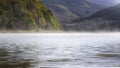 Fog rolling over lake surface on sunny autumn morning Royalty Free Stock Photo