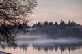 Fog sweeps over river during December sunset after snowfall