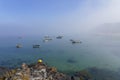 Fog swirls around small boats in Porthdinllaen harbour.in the summer sunshine Royalty Free Stock Photo