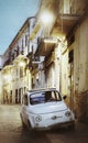 Vintage small Fiat 500 car parked in old town of Foggia at night. Puglia, Italy. Aging effect Royalty Free Stock Photo