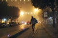 Foggy, christmas night scene, man carrying sack on his shoulders walking on the street