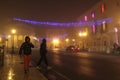 Foggy night scene. People walking on the streets of Foggia decorated with christmas lights