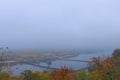 Foggy autumn colored landscape of Dnipro River.Pedestrian Bridge over river reflected in tranquil water surface Royalty Free Stock Photo