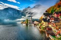 Foggy autumnal sunrise at famous Hallstatt lakeside town reflect