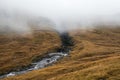 Foggy canyon, Faroe Islands. Mountain ravine. Foggy mountain gorge with a river