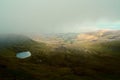 Foggy clouds and a hidden secret enchanted lake in the hills (Llyn Cwm Llwch) near Pen y Fan peak, Brecon Beacons , Wales, UK Royalty Free Stock Photo