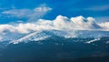 Foggy cloudy landscape seen from long distance of mountain ranges full of snow and giant clouds