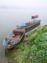 Foggy and  gloomy autumn scene of boats moored along riverbank. Royalty Free Stock Photo